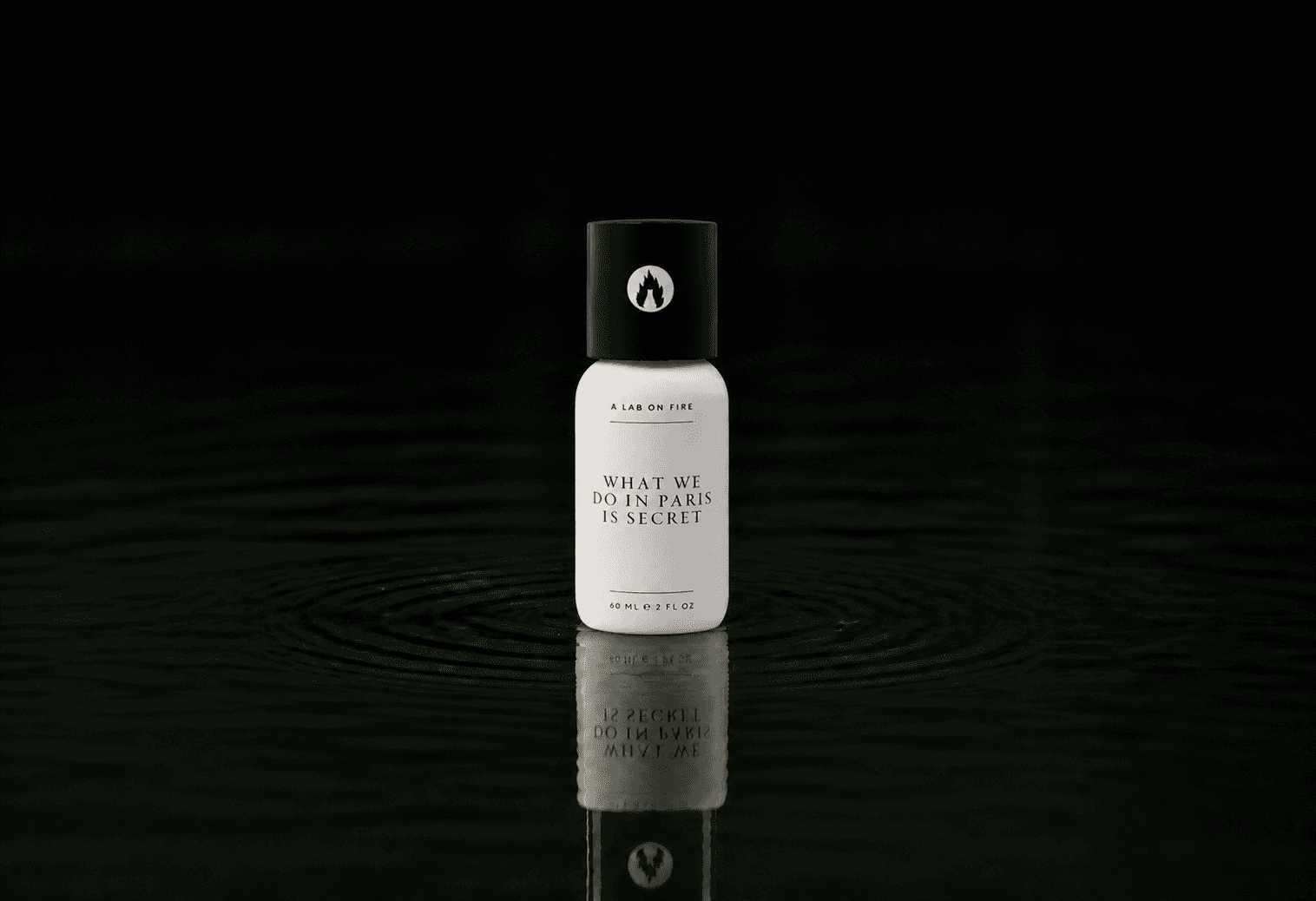 A Lab On Fire What We Do In Paris Is Secret fragrance bottle floating above dark water