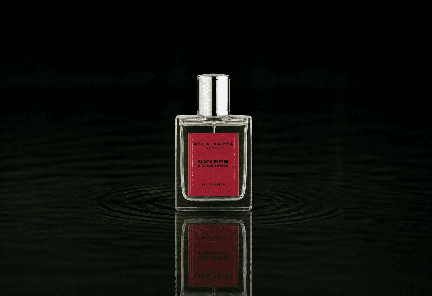 Acca Kappa Black Pepper & Sandalwood fragrance bottle floating above dark water