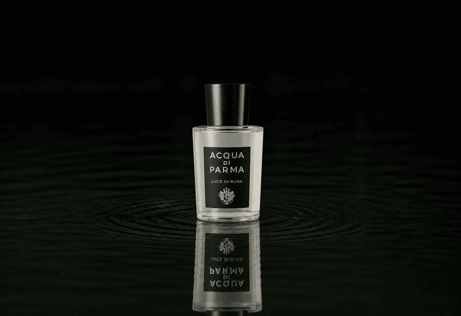 Acqua Di Parma Luce Di Rosa fragrance bottle floating above dark water