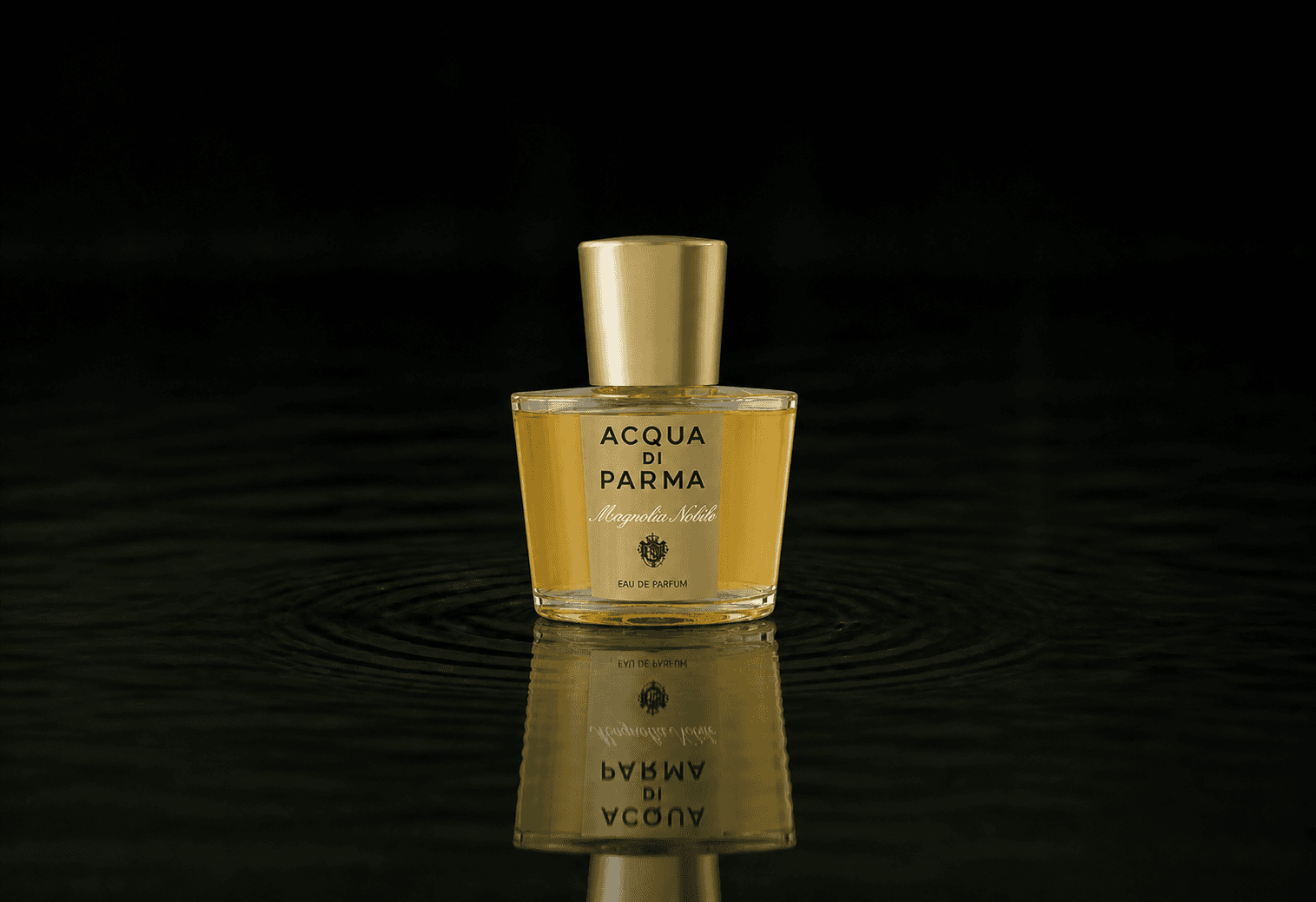 Acqua Di Parma Magnolia fragrance bottle floating above dark water