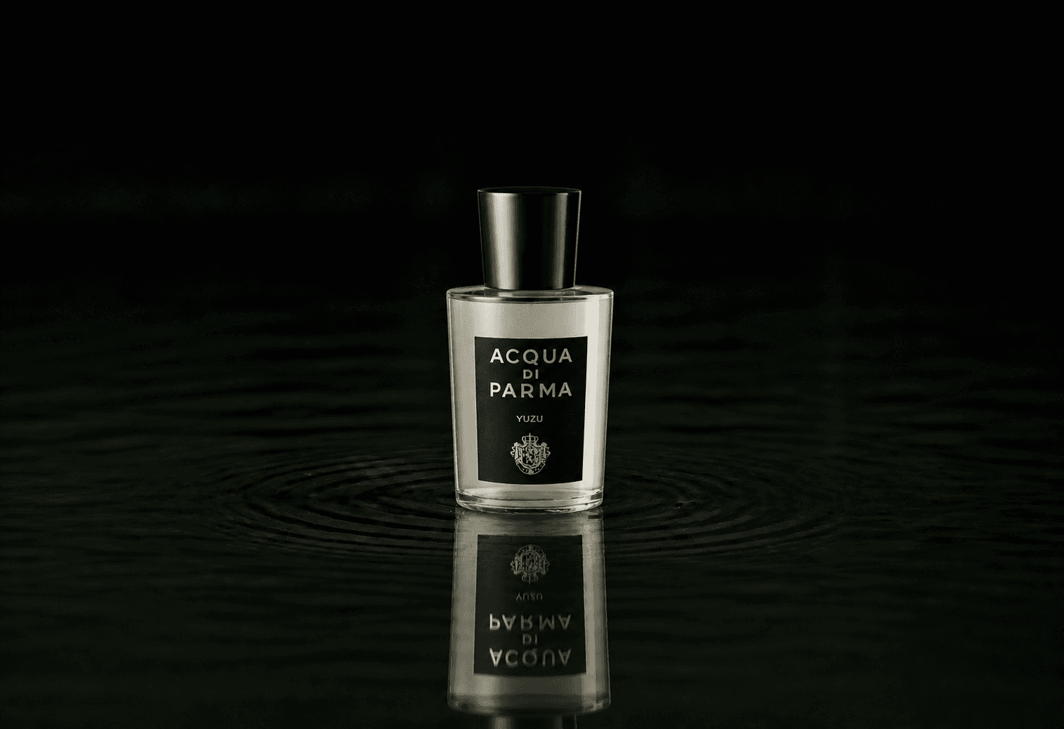 Acqua Di Parma Yuzu fragrance bottle floating above dark water