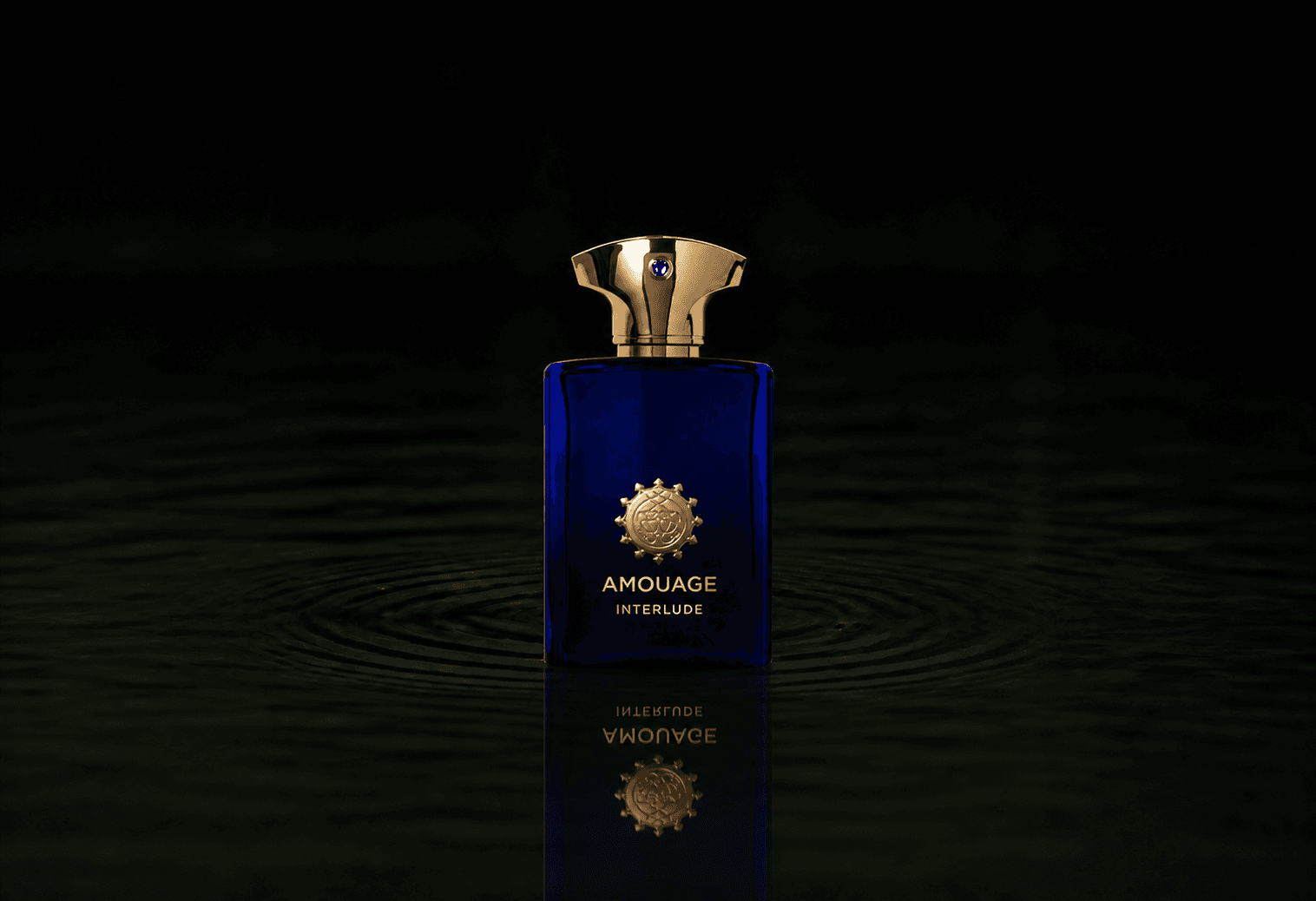 Amouage Interlude Man fragrance bottle floating above dark water