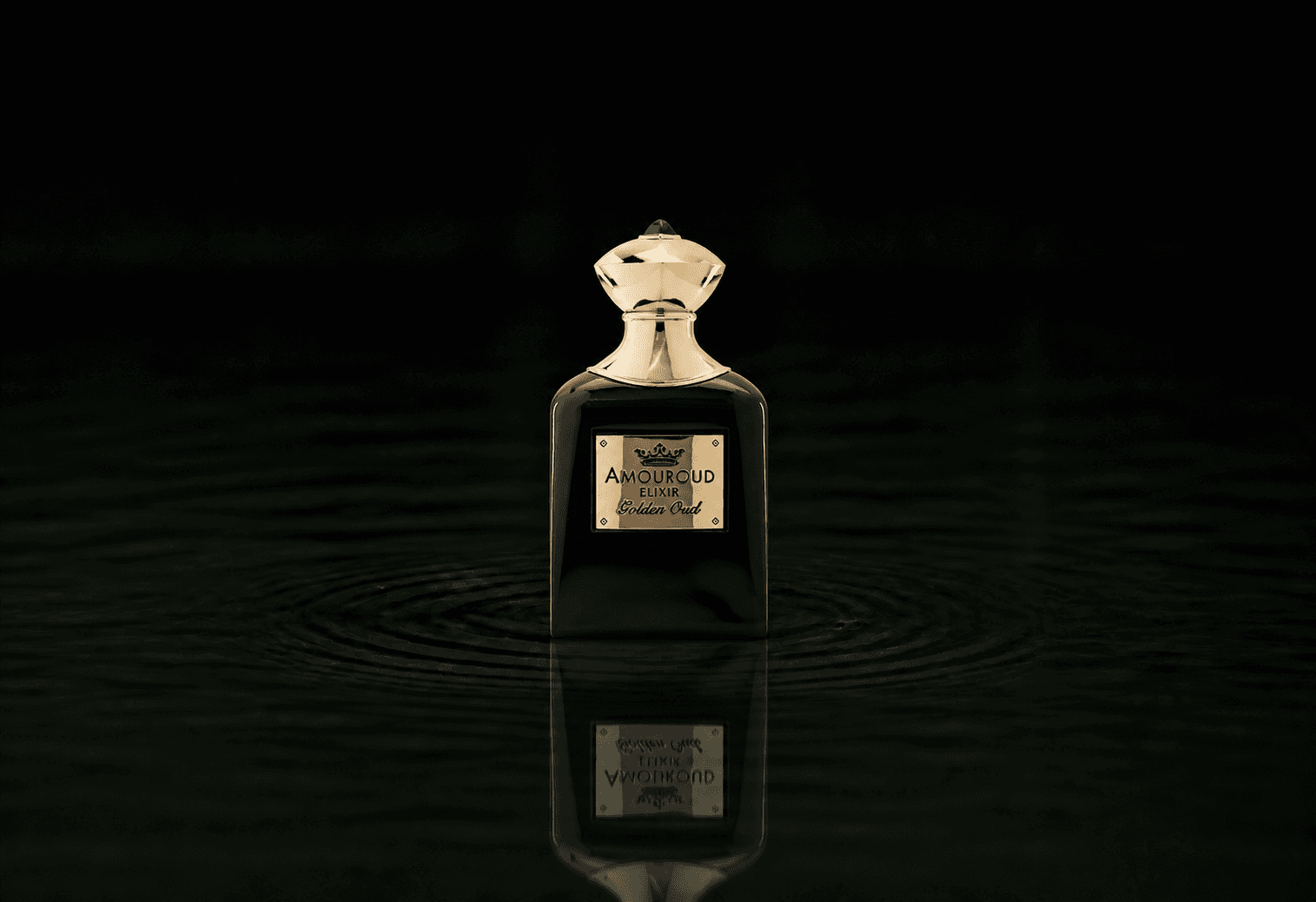 Amouroud Golden Oud Elixir fragrance bottle floating above dark water
