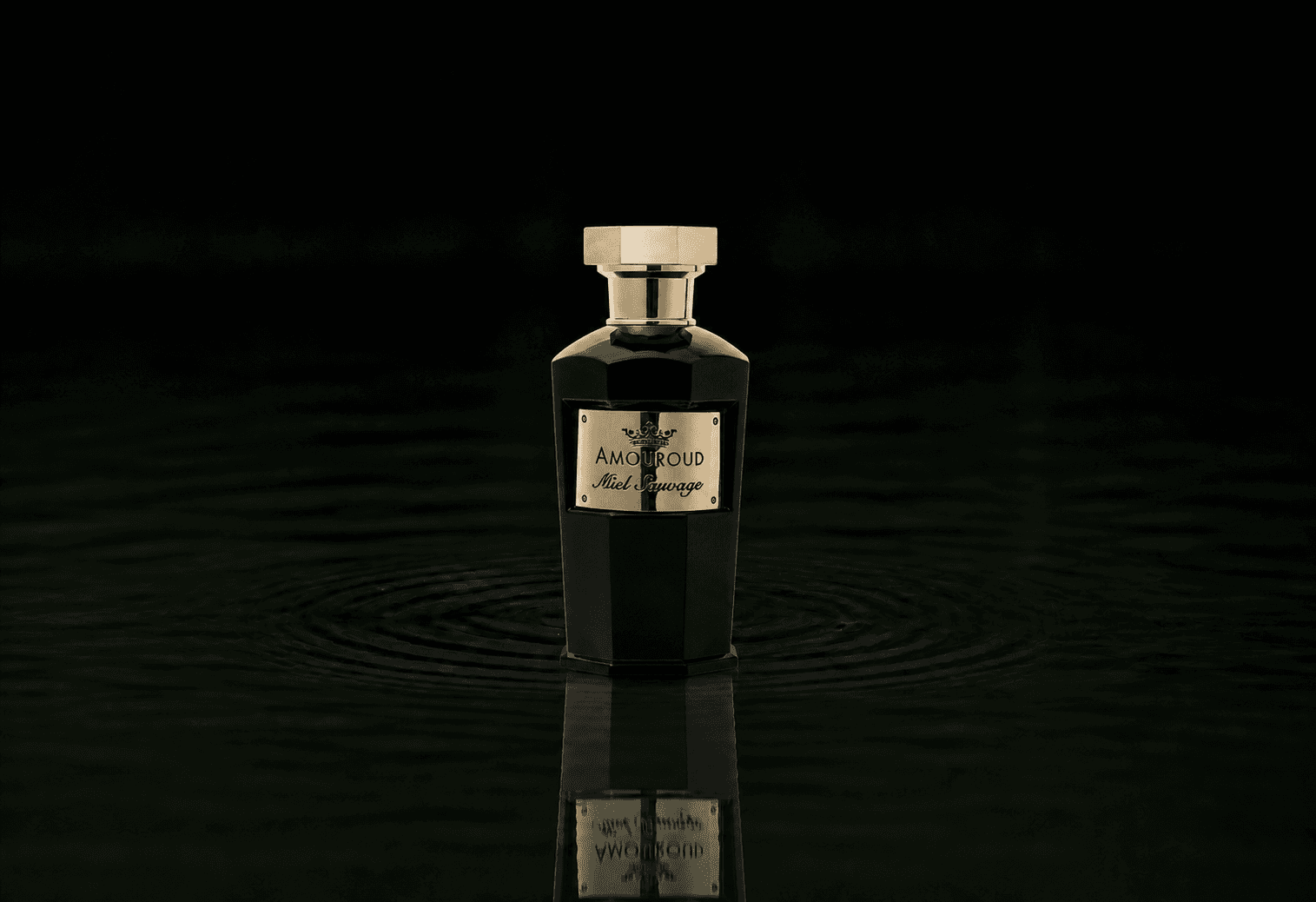 Amouroud Miel Sauvage fragrance bottle floating above dark water