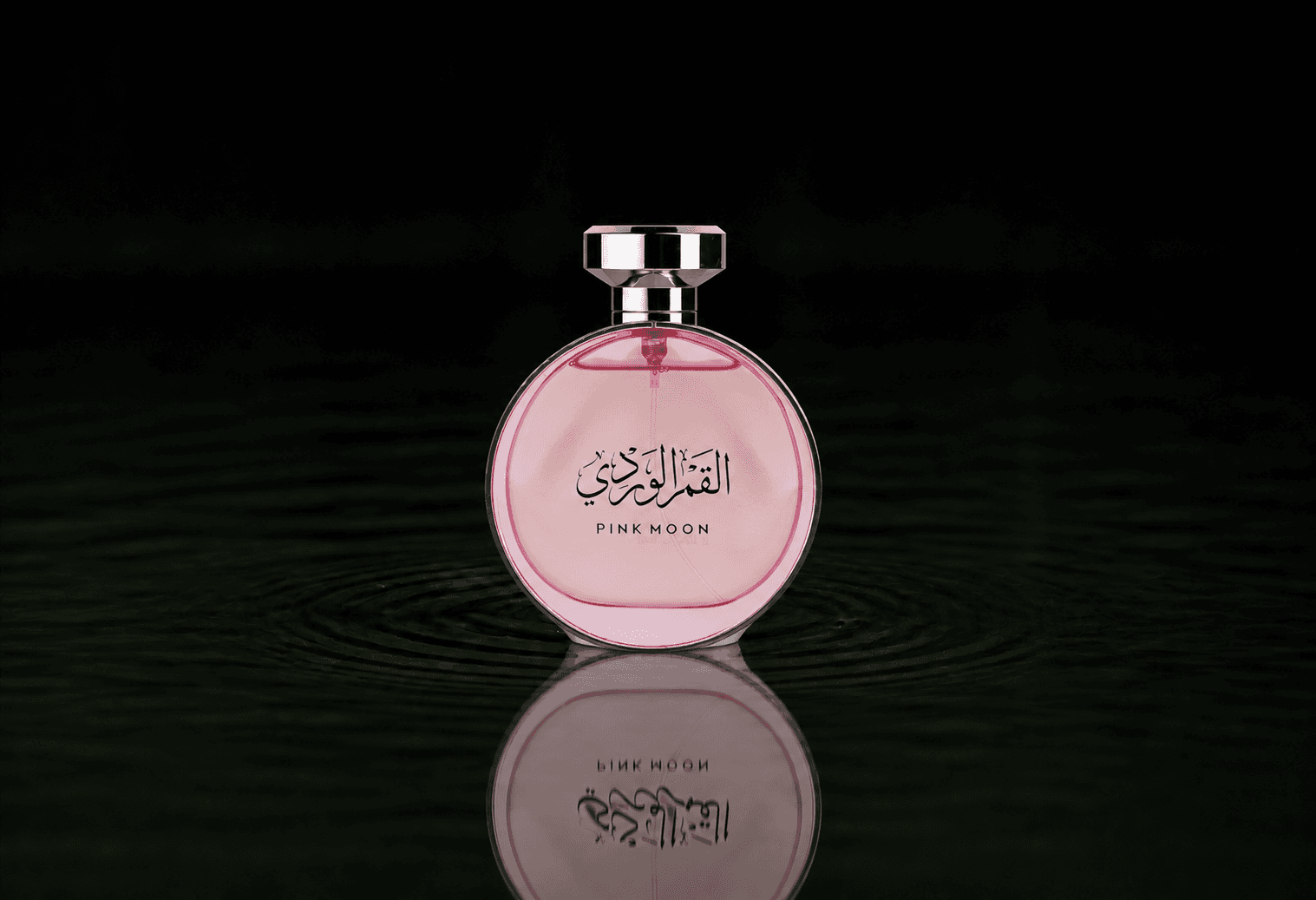 Arabian Oud Pink Moon fragrance bottle floating above dark water