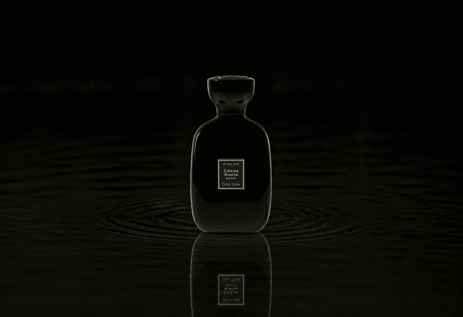 Atelier Des Ors Cocoa Kimiya fragrance bottle floating above dark water