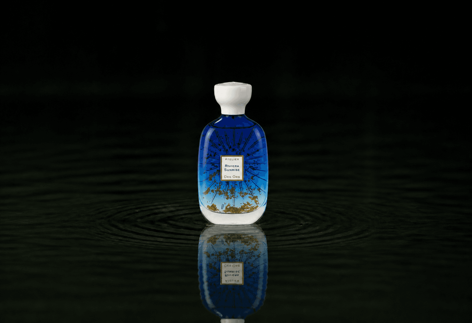 Atelier Des Ors Riviera Sunrise fragrance bottle floating above dark water