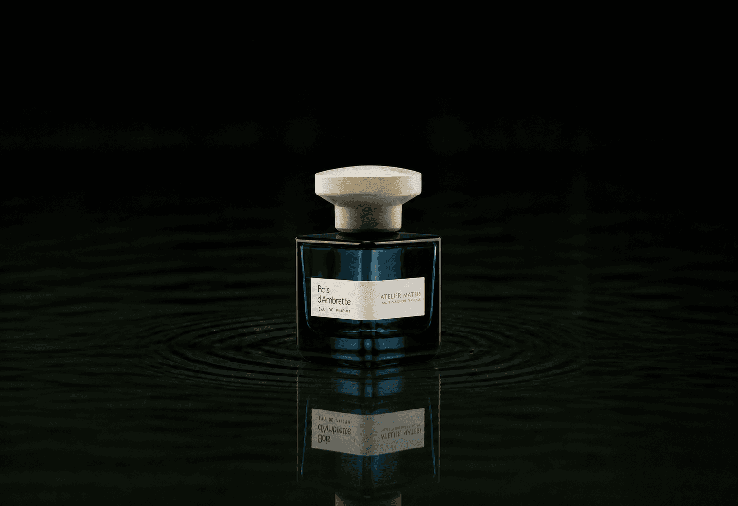 Atelier Materi Bois D'Ambrette fragrance bottle floating above dark water