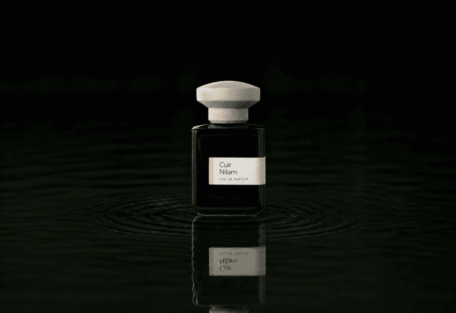 Atelier Materi Cuir Nilam fragrance bottle floating above dark water