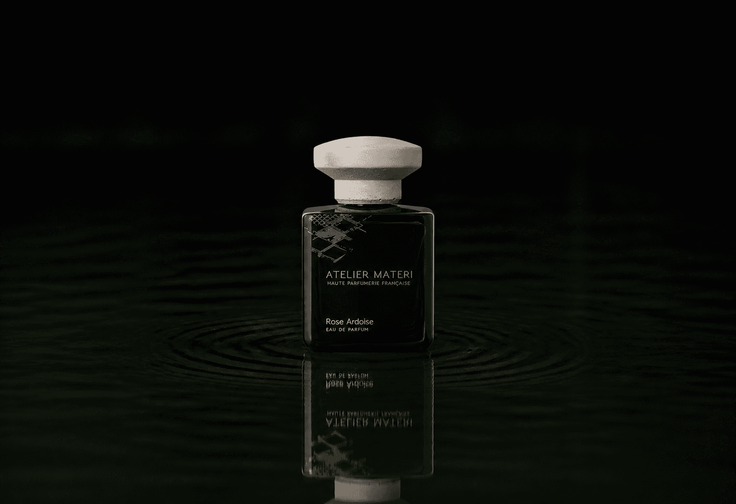 Atelier Materi Rose Ardoise fragrance bottle floating above dark water