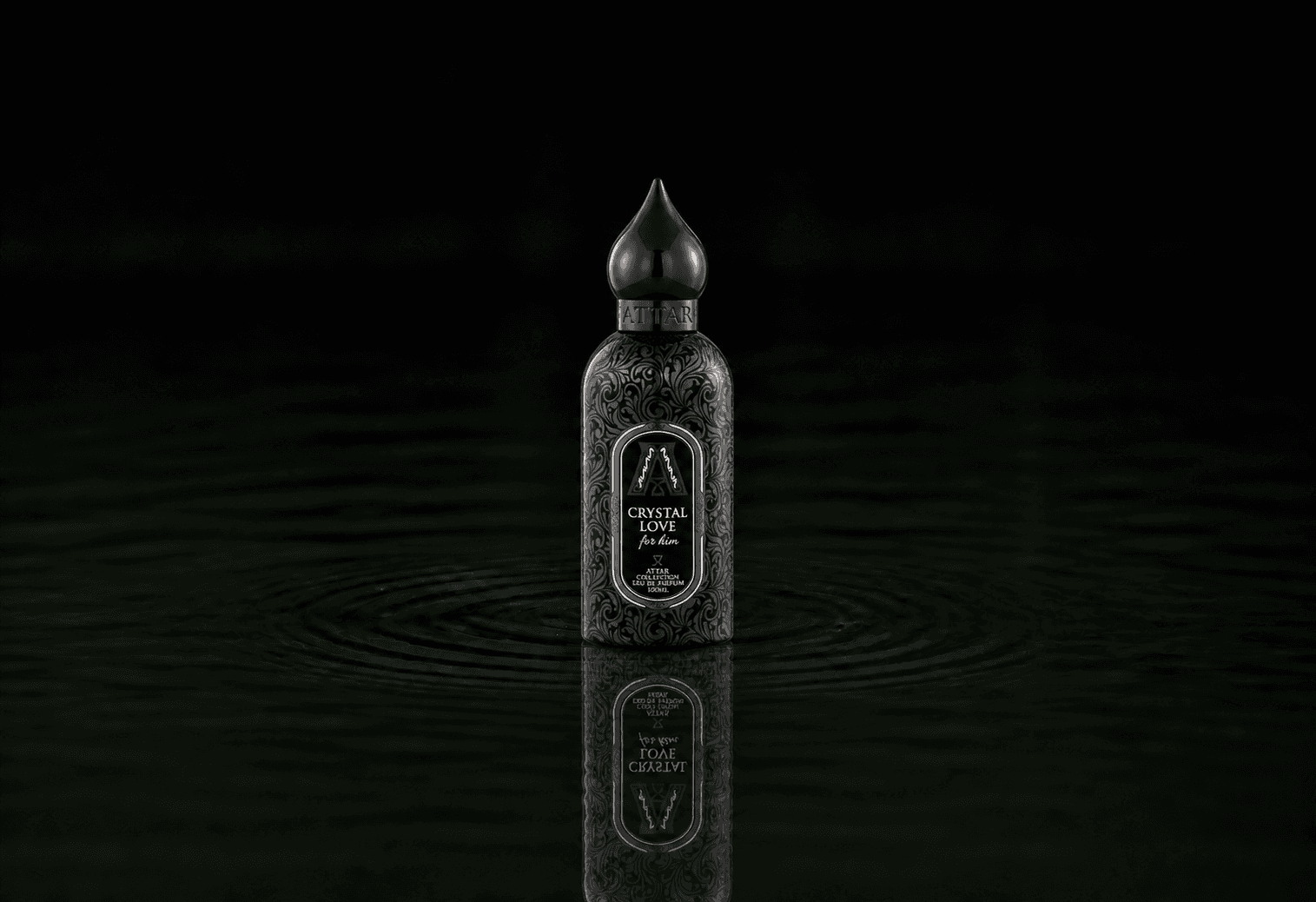 Attar Collection Crystal Love For Him fragrance bottle floating above dark water
