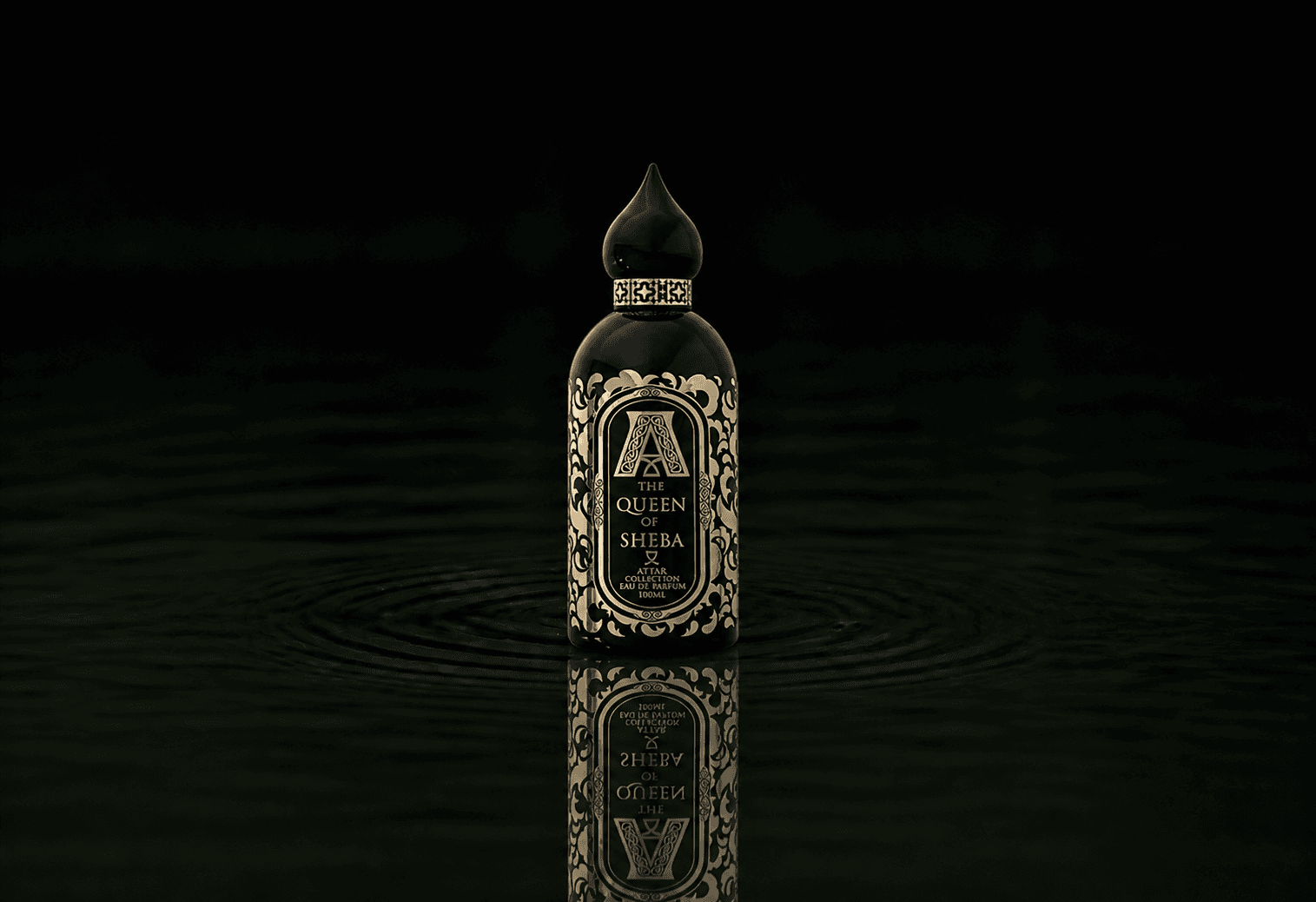 Attar Collection The Queen Of Sheba fragrance bottle floating above dark water