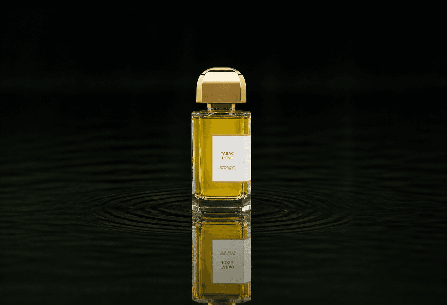 BDK Parfums Tabac Rose fragrance bottle floating above dark water