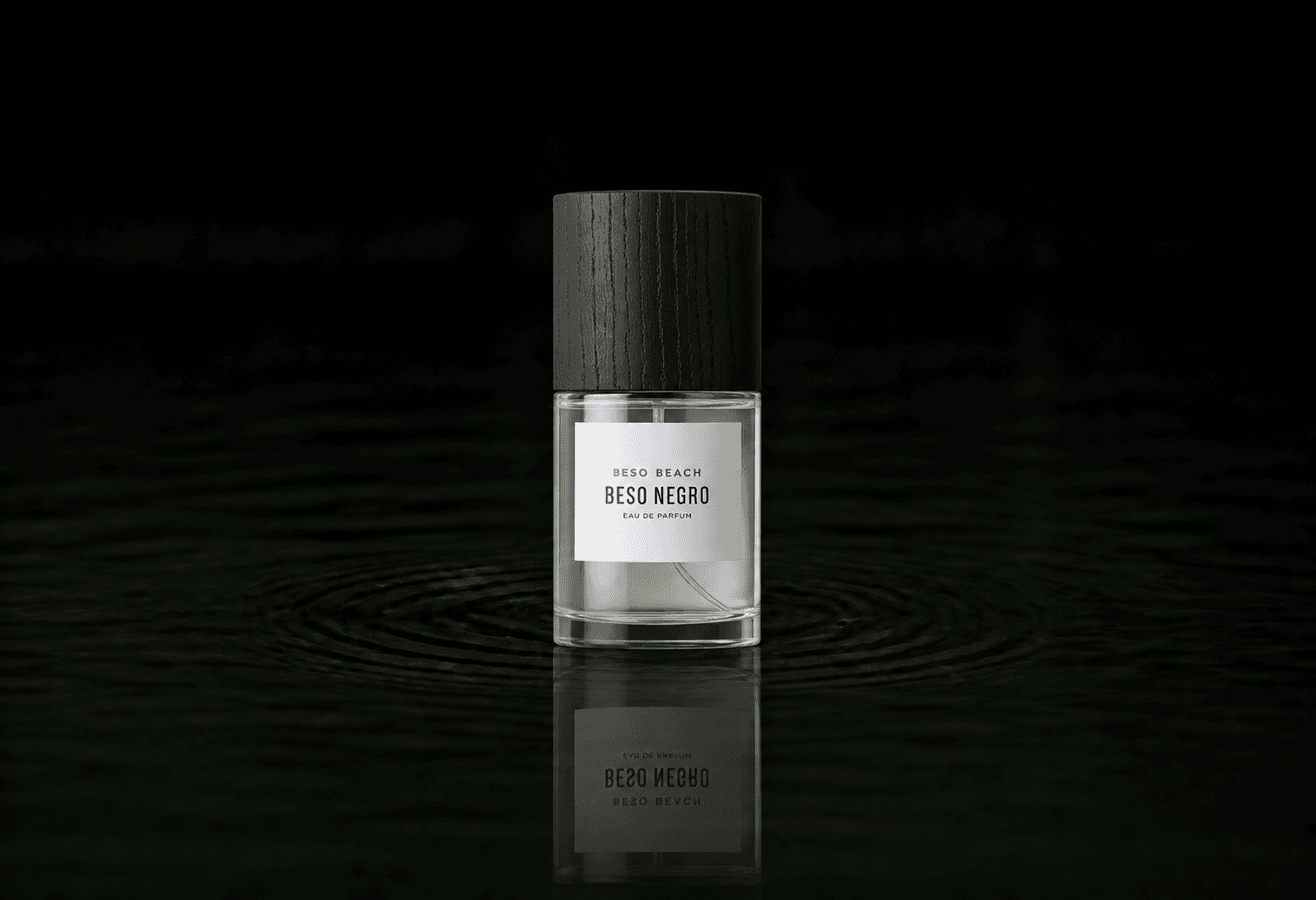 Beso Beach Perfumes - Beso Negro fragrance bottle floating above dark water