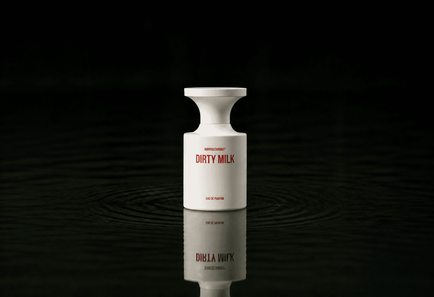 BORNTOSTANDOUT Dirty Milk fragrance bottle floating above dark water