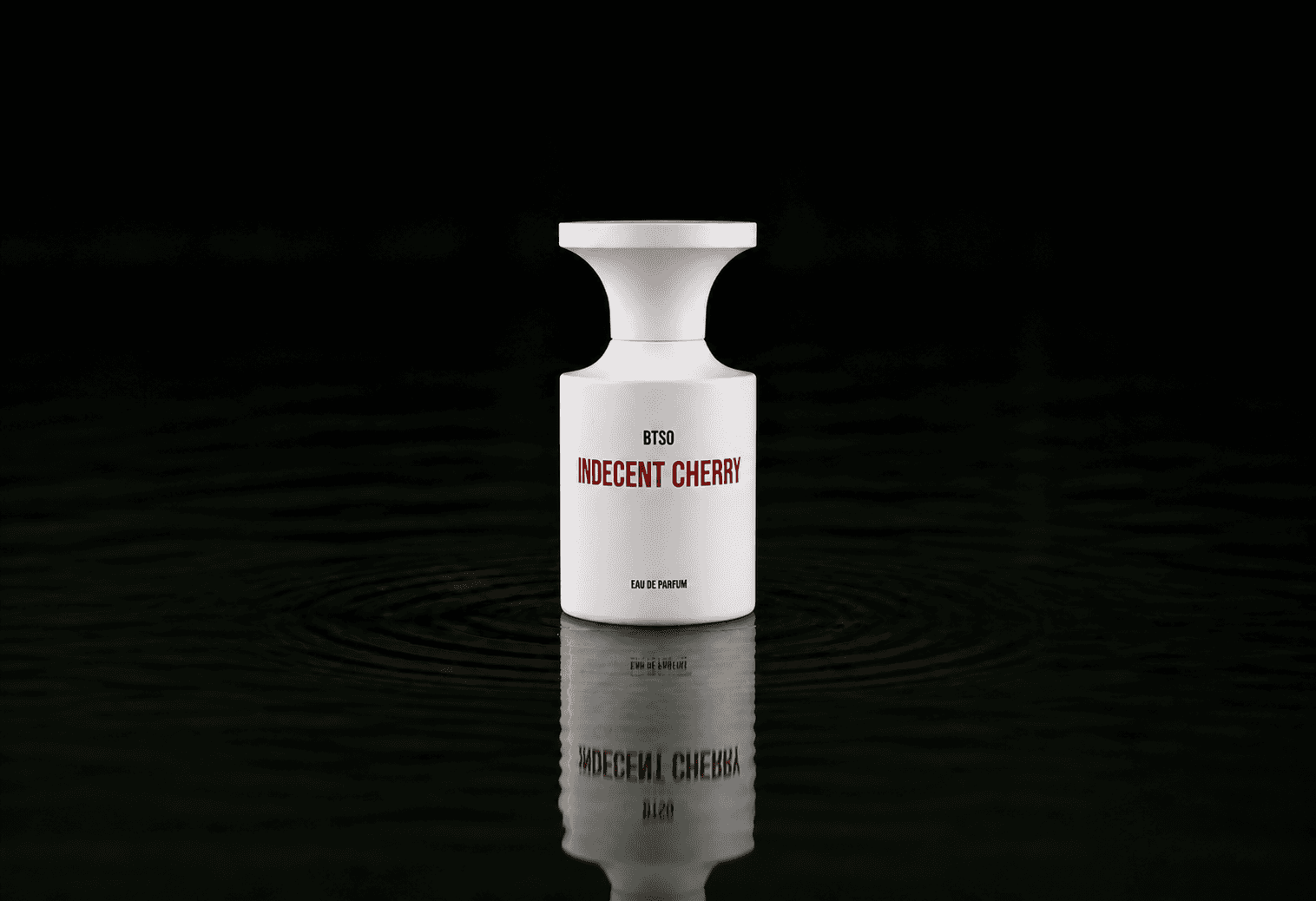 BORNTOSTANDOUT Indecent Cherry fragrance bottle floating above dark water
