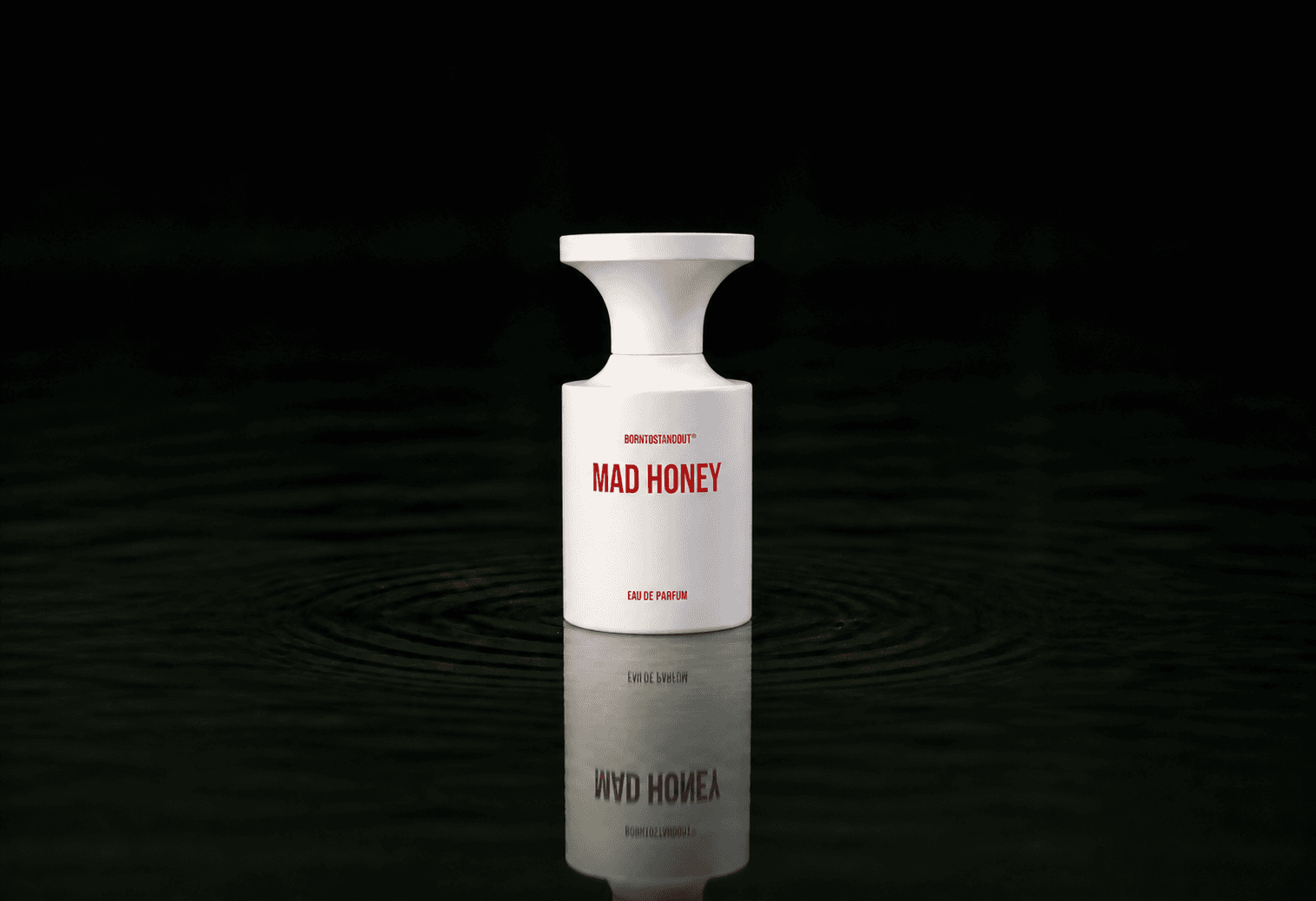 BORNTOSTANDOUT Mad Honey fragrance bottle floating above dark water