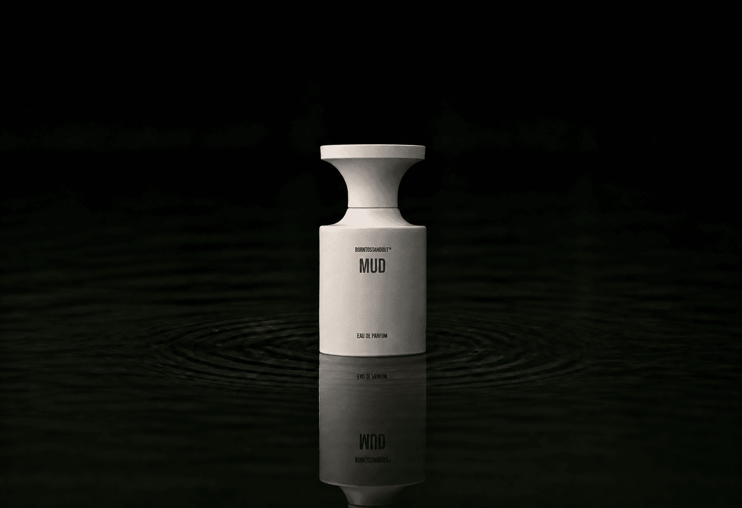 BORNTOSTANDOUT Mud fragrance bottle floating above dark water