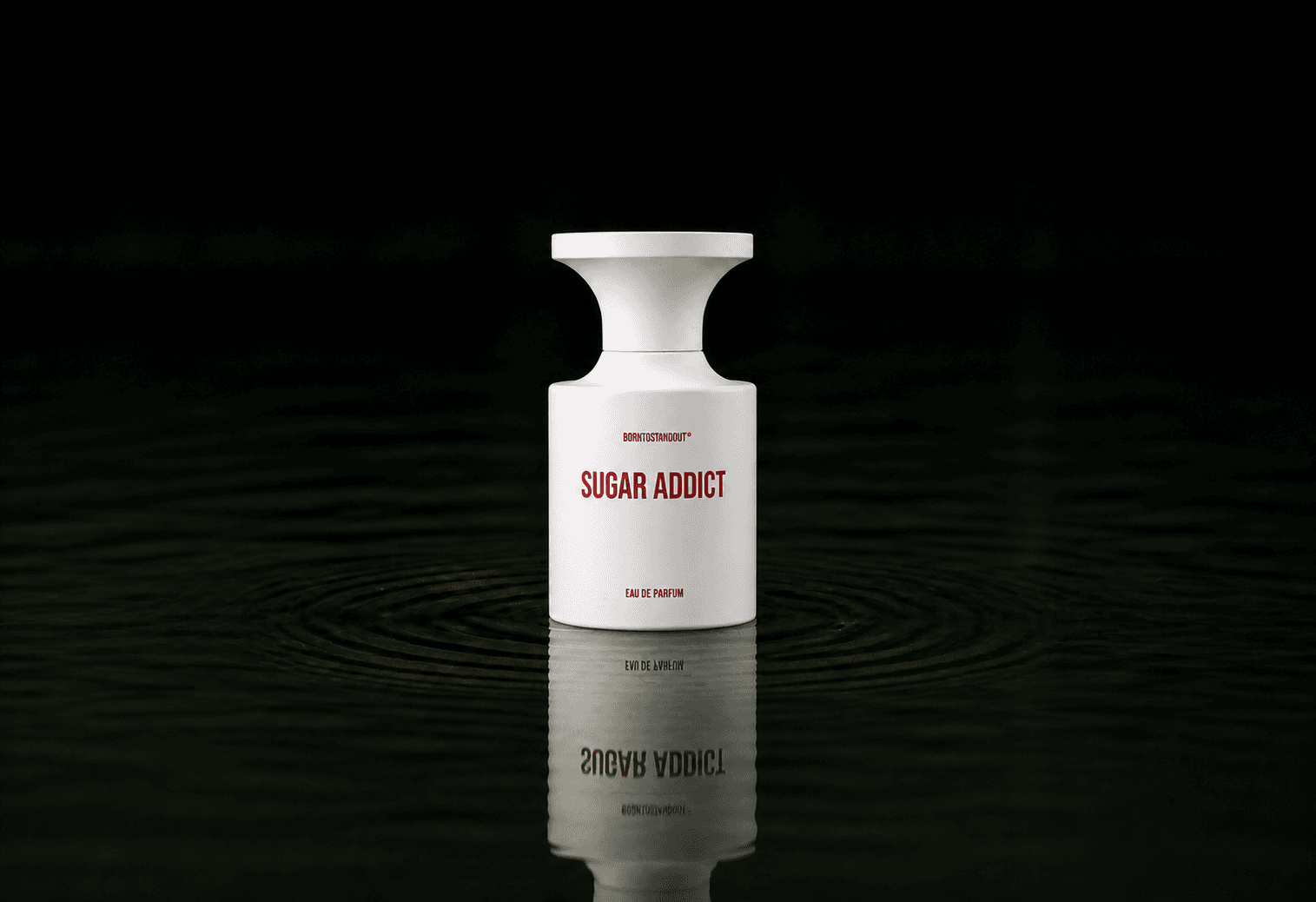 BORNTOSTANDOUT Sugar Addict fragrance bottle floating above dark water