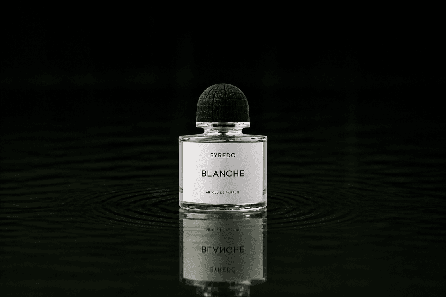 Byredo Parfums - Blanche Absolu fragrance bottle floating above dark water