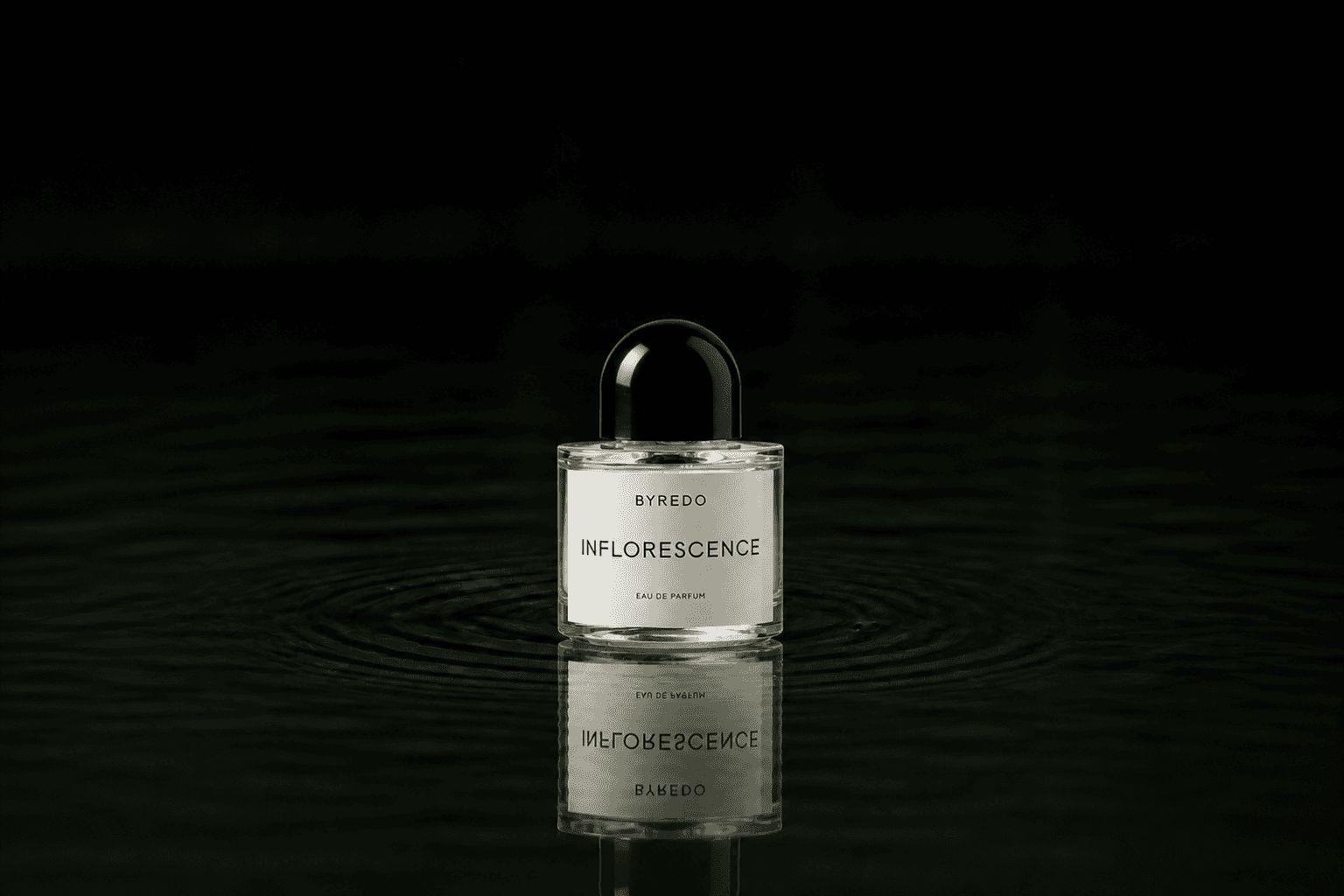 Byredo Parfums - Inflorescence fragrance bottle floating above dark water
