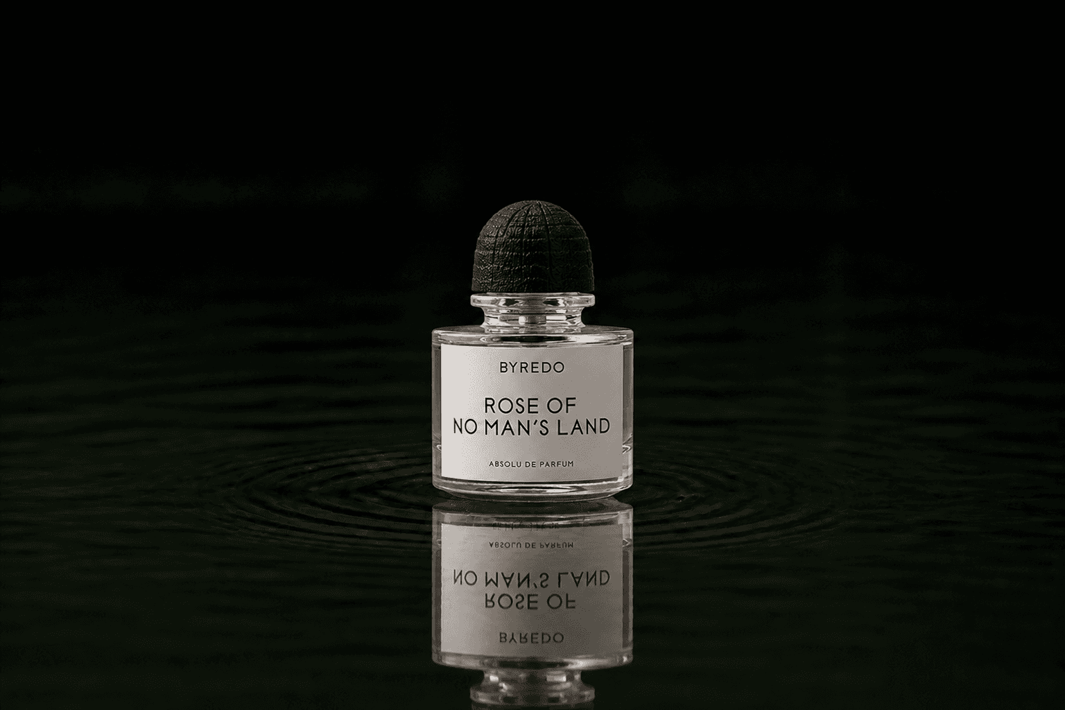 Byredo Perfume - Absolu Collection - Rose Of No Man's Land Absolu de Parfum fragrance bottle floating above dark water