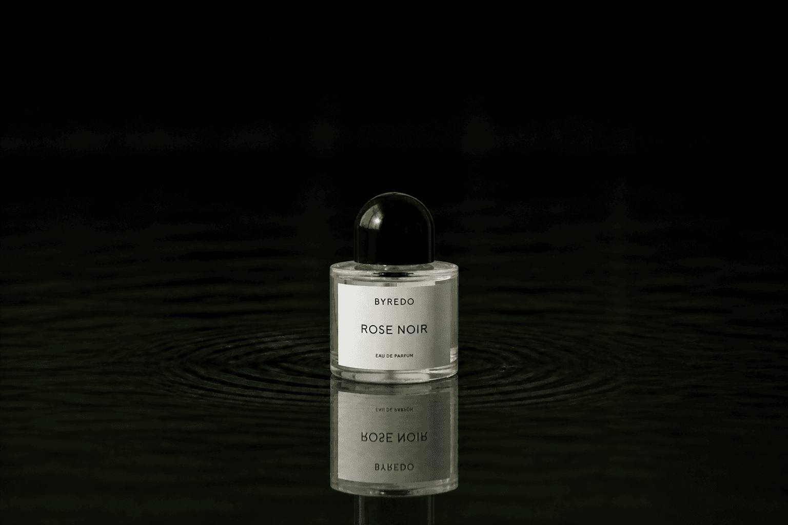 Byredo Rose Noir fragrance bottle floating above dark water
