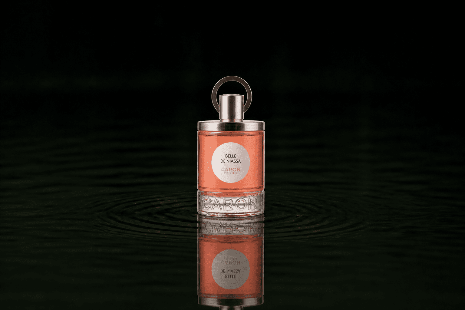 Caron Belle De Niassa fragrance bottle floating above dark water