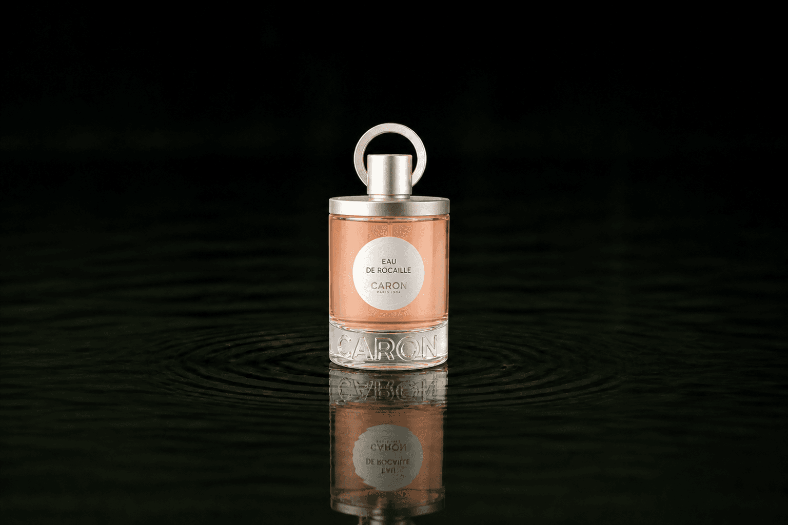 Caron Eau De Rocaille fragrance bottle floating above dark water