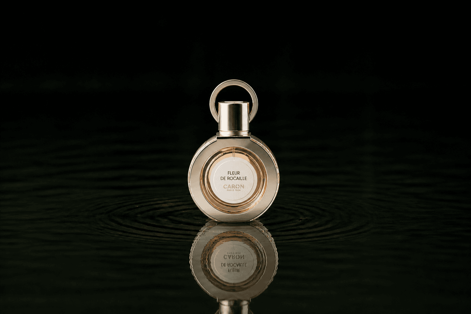 Caron Fleur De Rocaille fragrance bottle floating above dark water