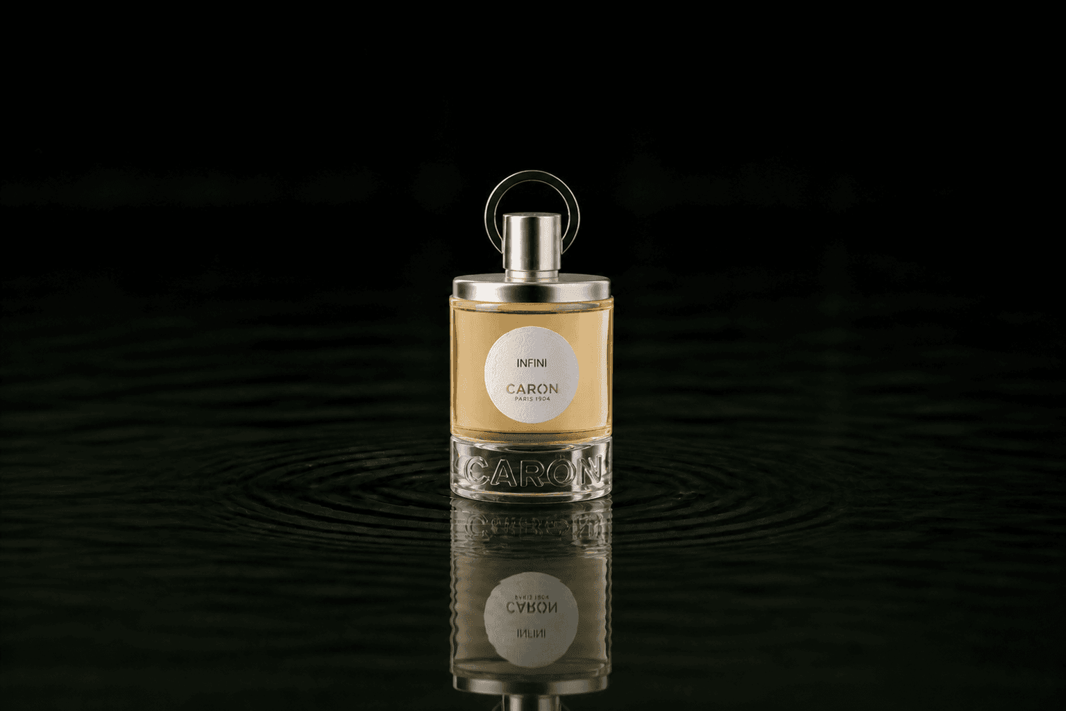 Caron Infini fragrance bottle floating above dark water