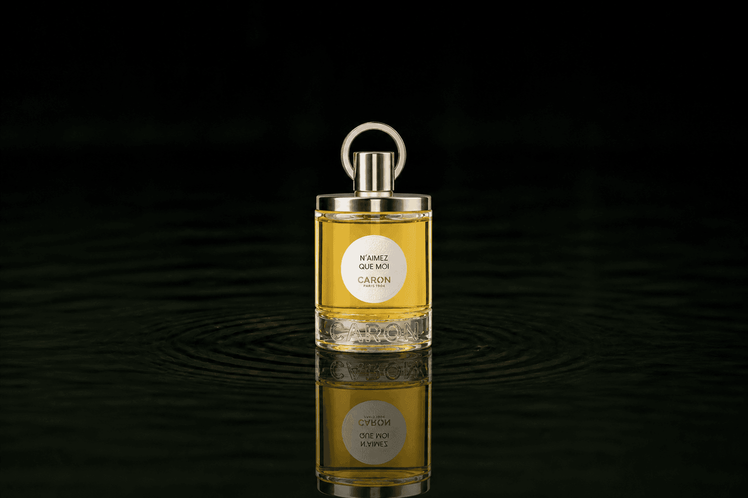 Caron N'aimez Que Moi Perfume fragrance bottle floating above dark water
