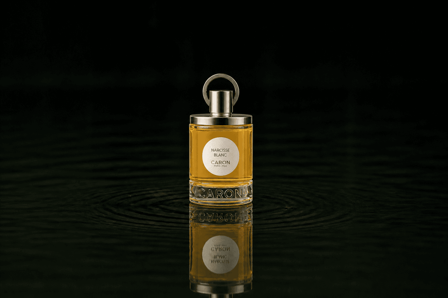 Caron Narcisse Blanc fragrance bottle floating above dark water