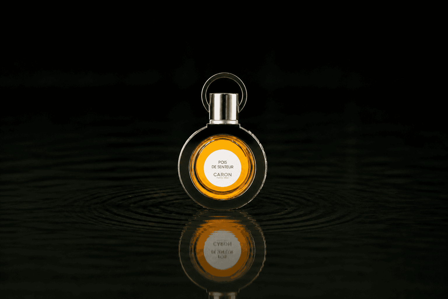 Caron Pois De Senteur Perfume fragrance bottle floating above dark water