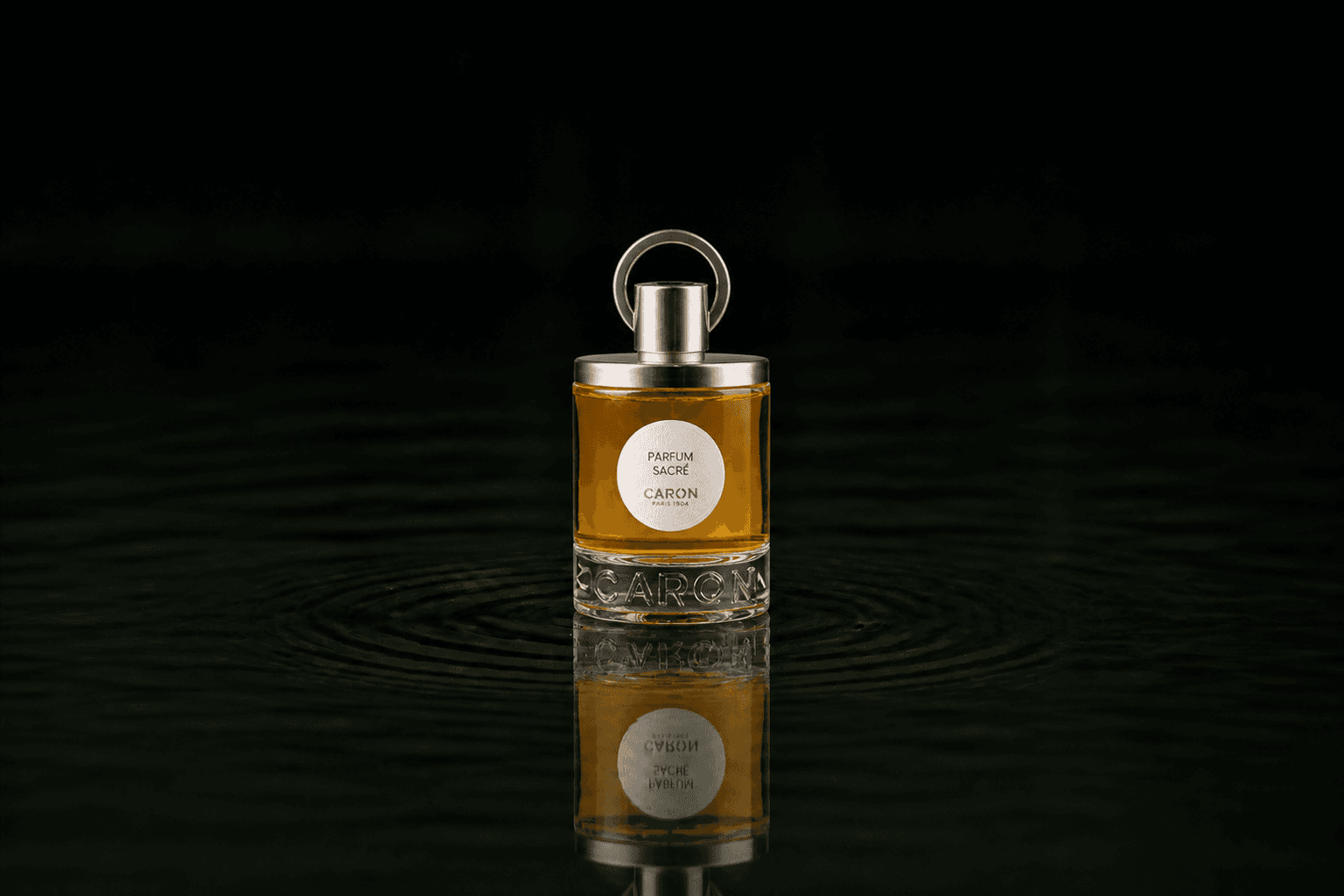 Caron Sacré Parfum fragrance bottle floating above dark water