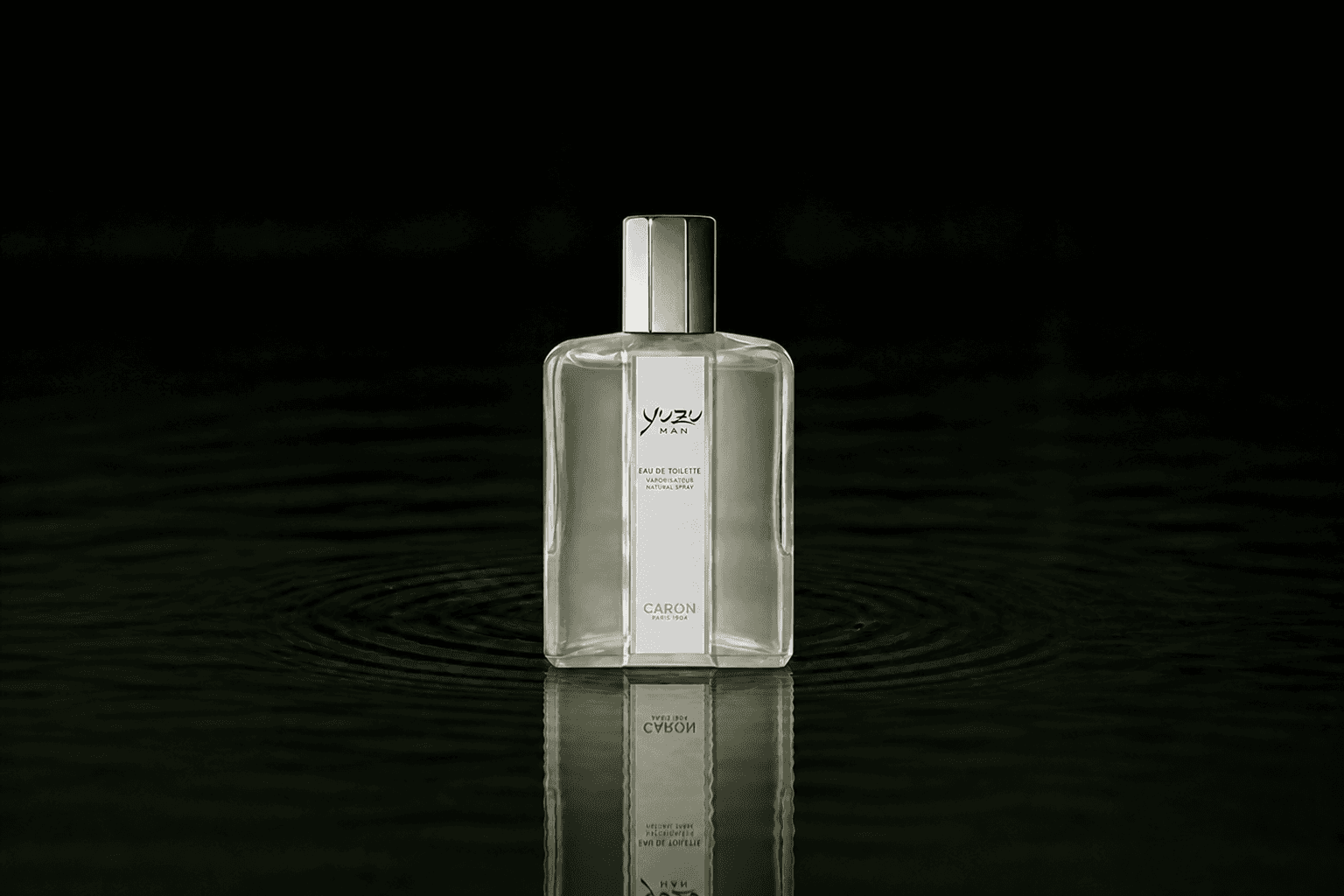 Caron Yuzu Man fragrance bottle floating above dark water