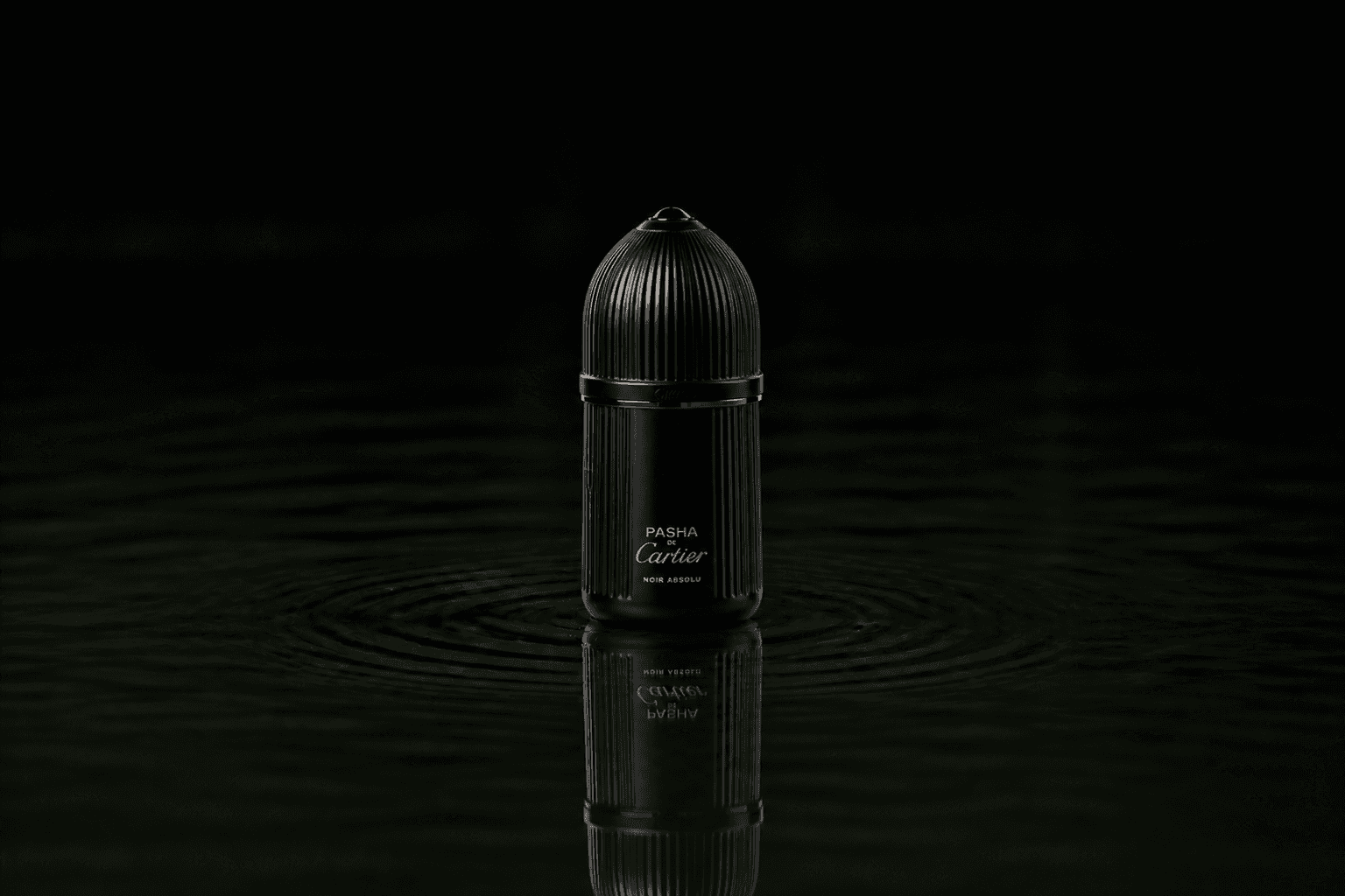 Cartier Pasha Noir Absolu fragrance bottle floating above dark water