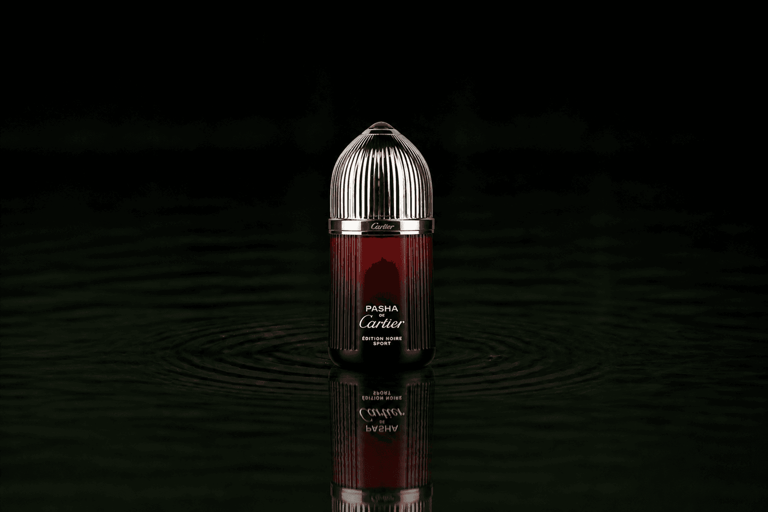 Cartier Pasha Noir Sport fragrance bottle floating above dark water