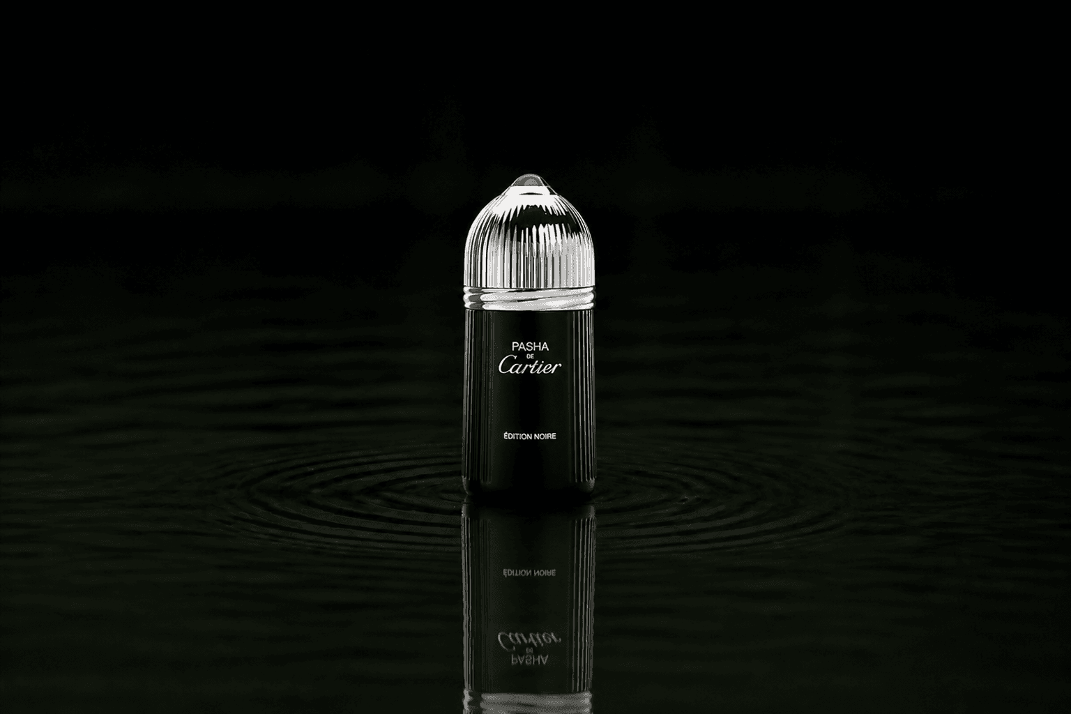 Cartier Pasha Noir fragrance bottle floating above dark water