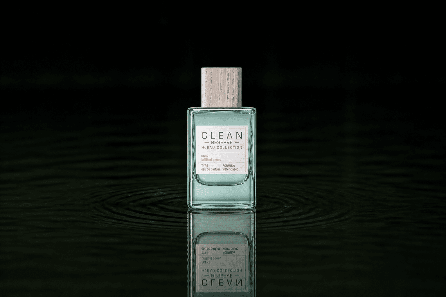 Clean Reserve H2EAU Brilliant Peony fragrance bottle floating above dark water