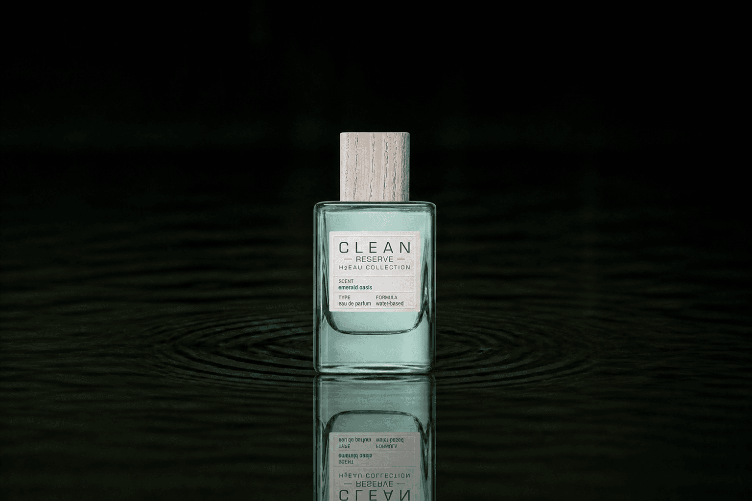 Clean Reserve H2EAU Emerald Oasis fragrance bottle floating above dark water
