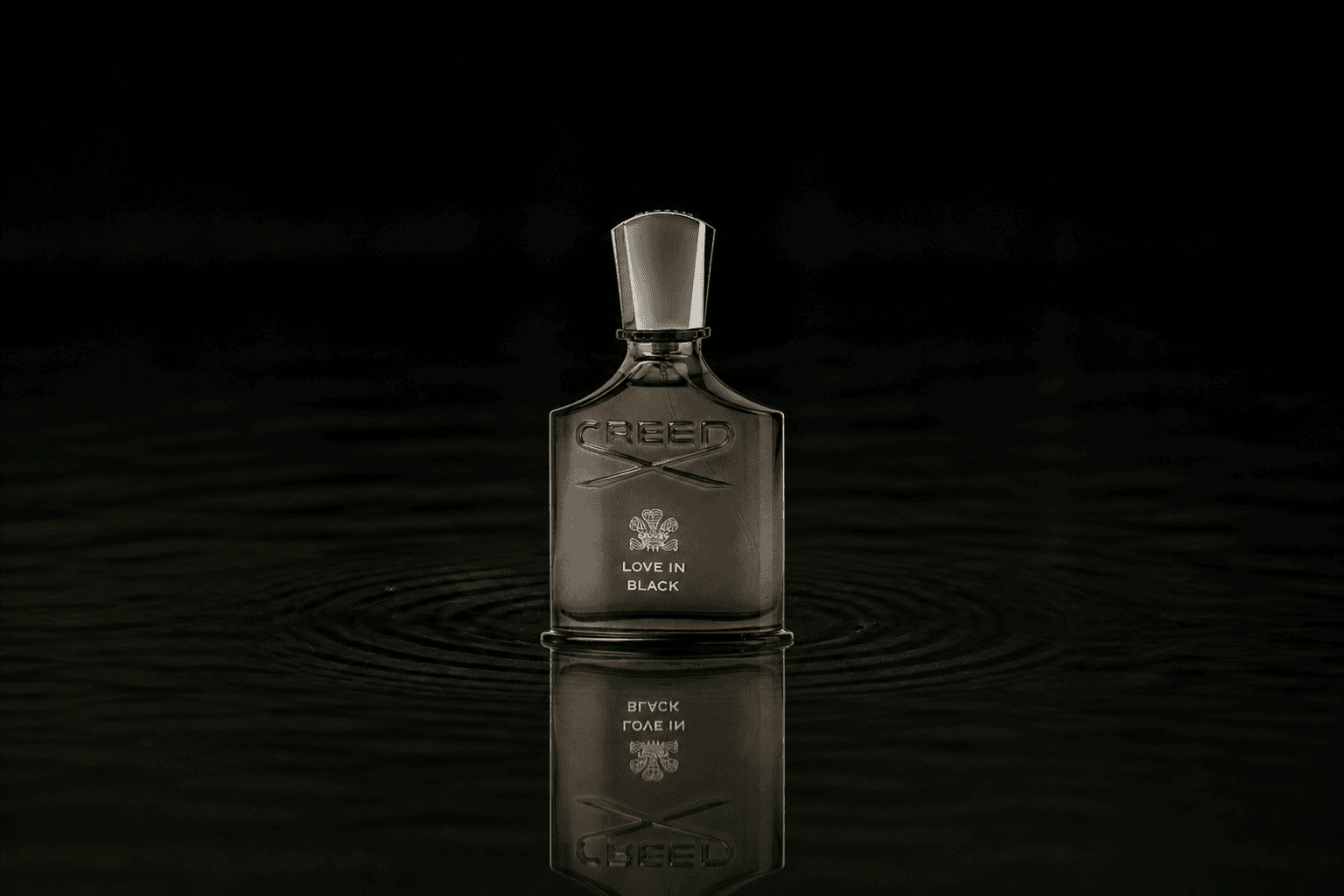Creed Love in Black fragrance bottle floating above dark water