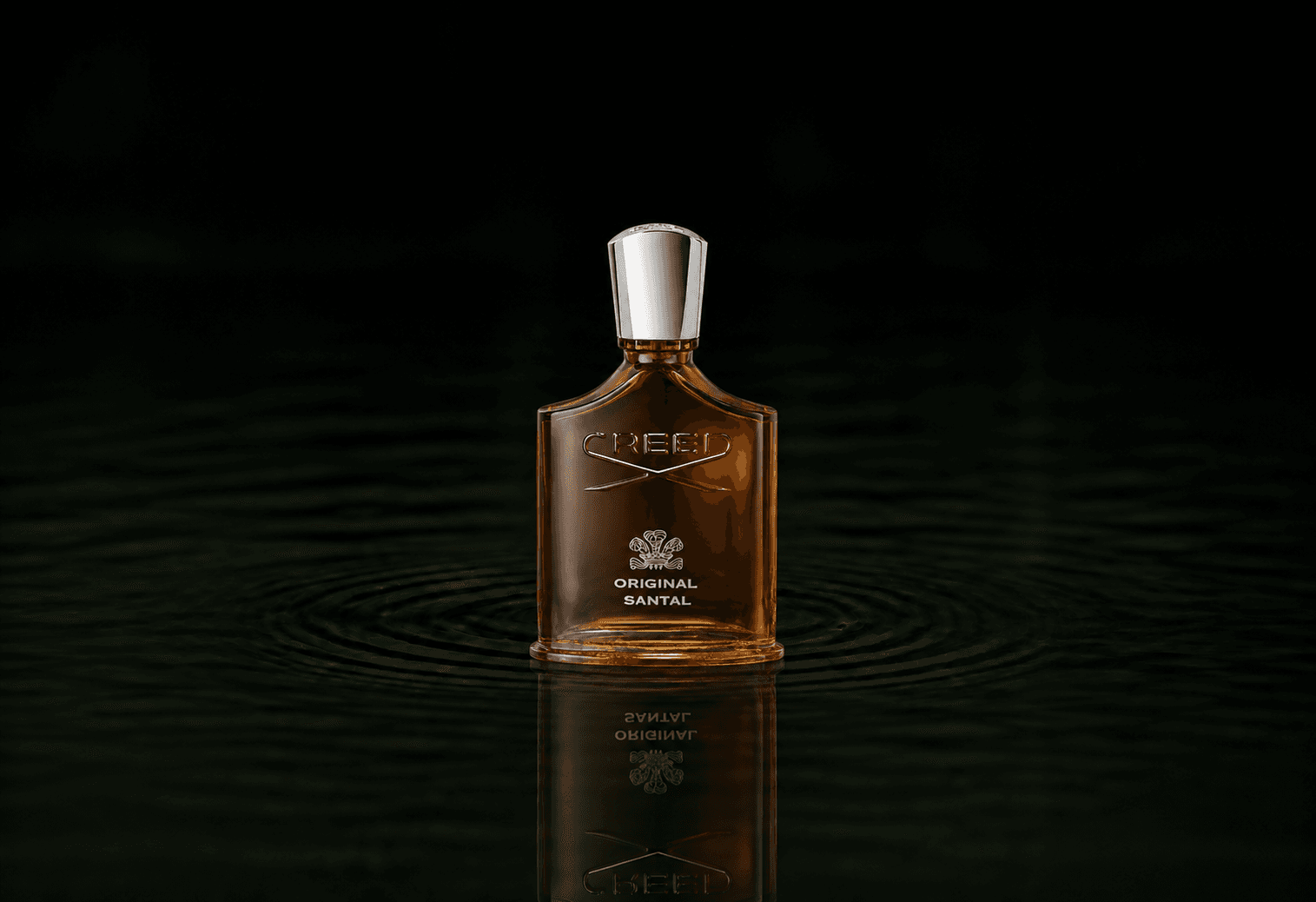 Creed Original Santal fragrance bottle floating above dark water