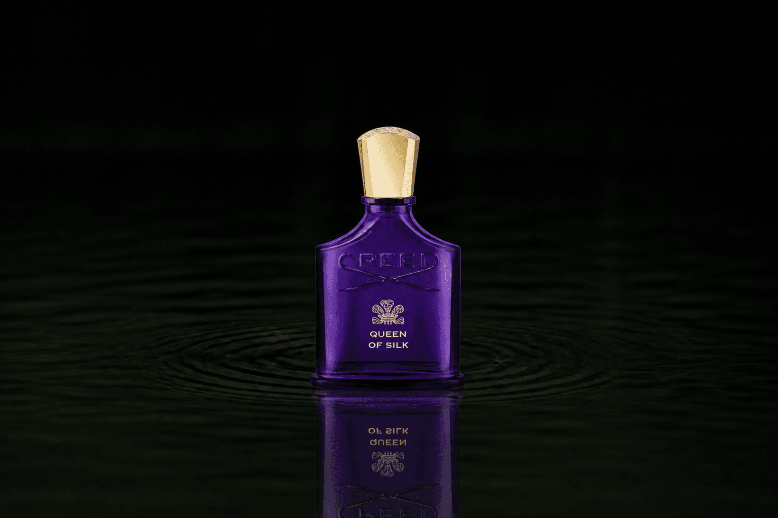 Creed Queen Of Silk fragrance bottle floating above dark water