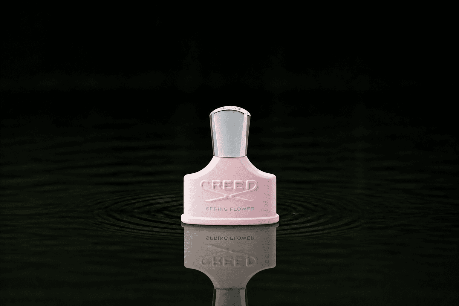 Creed Spring Flower fragrance bottle floating above dark water