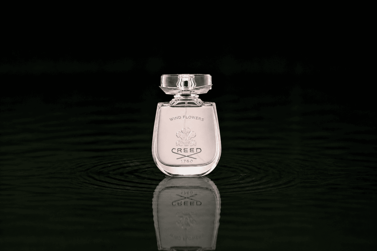 Creed Wind Flowers fragrance bottle floating above dark water