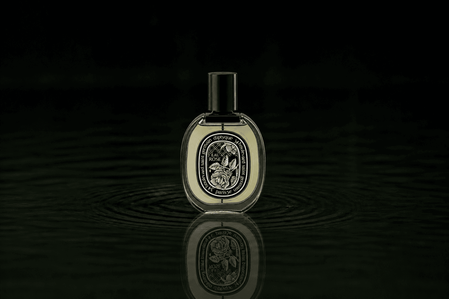Diptyque Eau Rose fragrance bottle floating above dark water