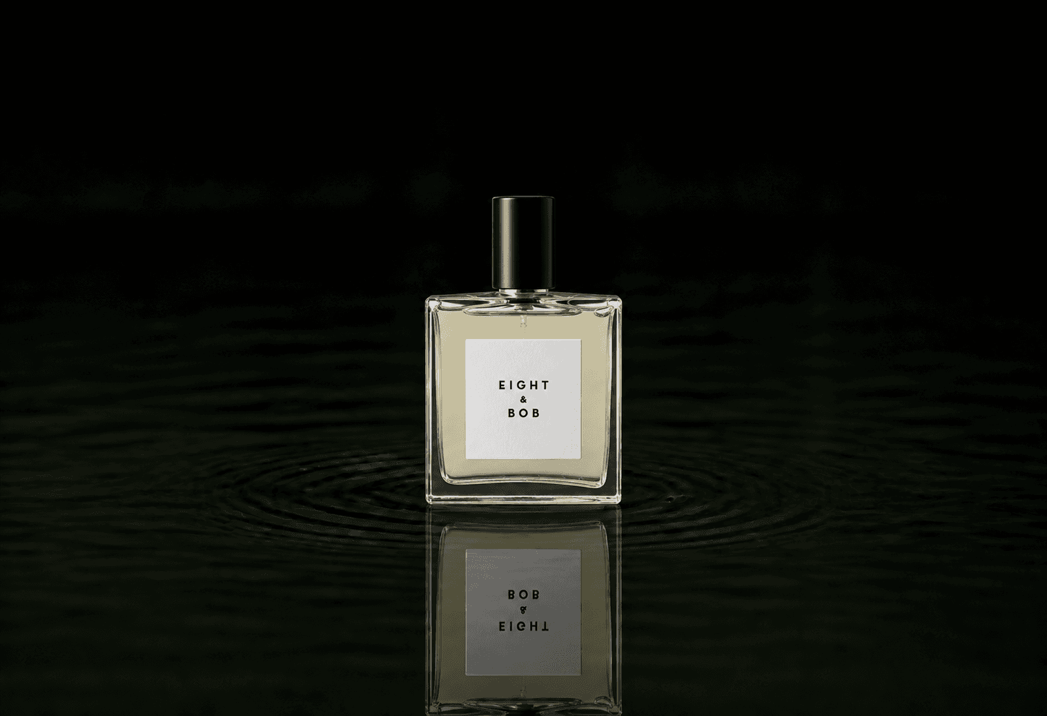 Eight & Bob Original fragrance bottle floating above dark water