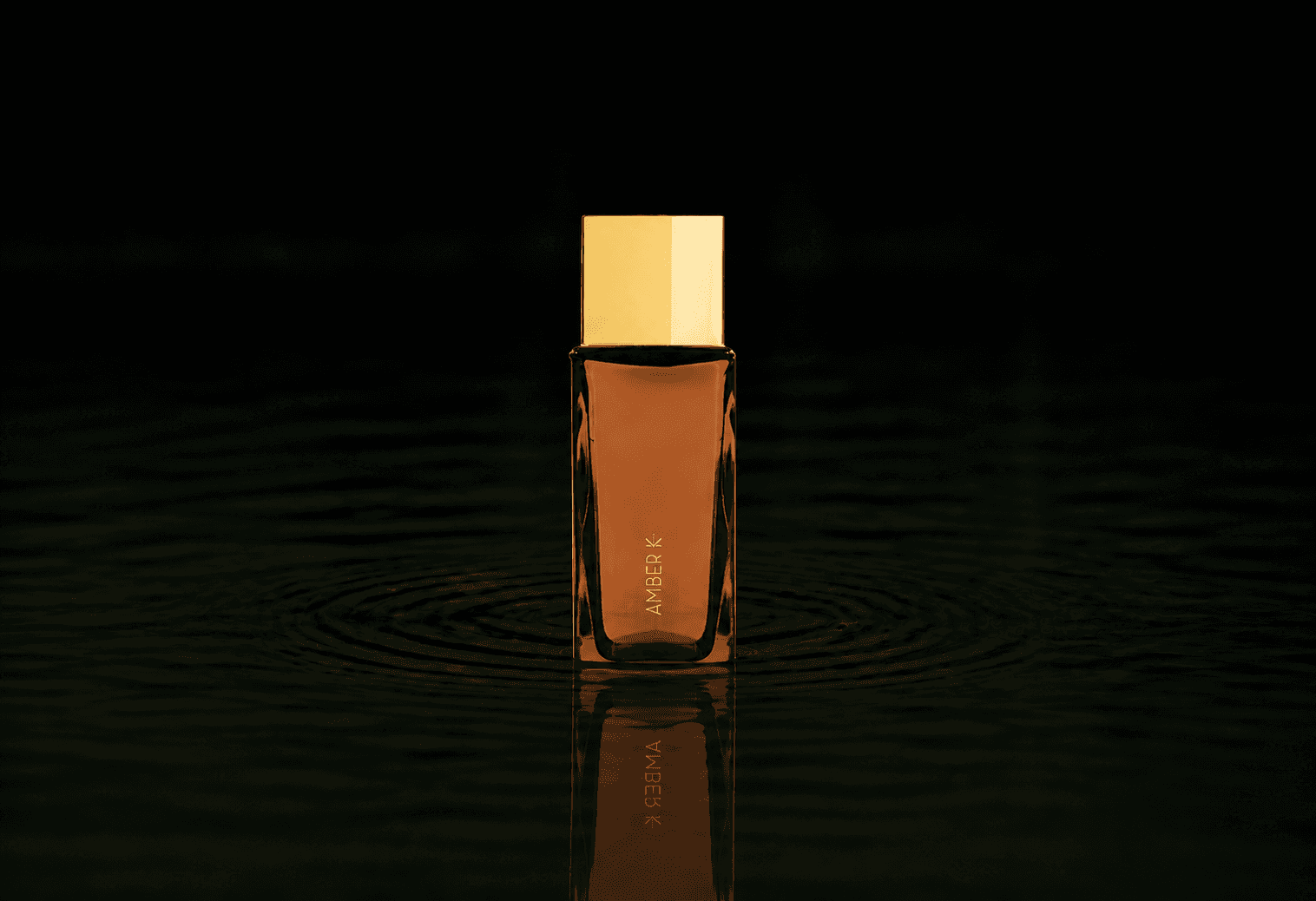 Ella K Amber K fragrance bottle floating above dark water