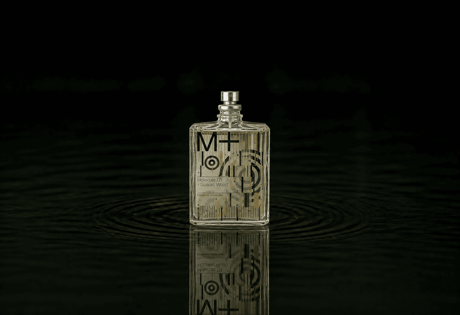 Escentric Molecules Molecule 01 + Guaiac Wood fragrance bottle floating above dark water